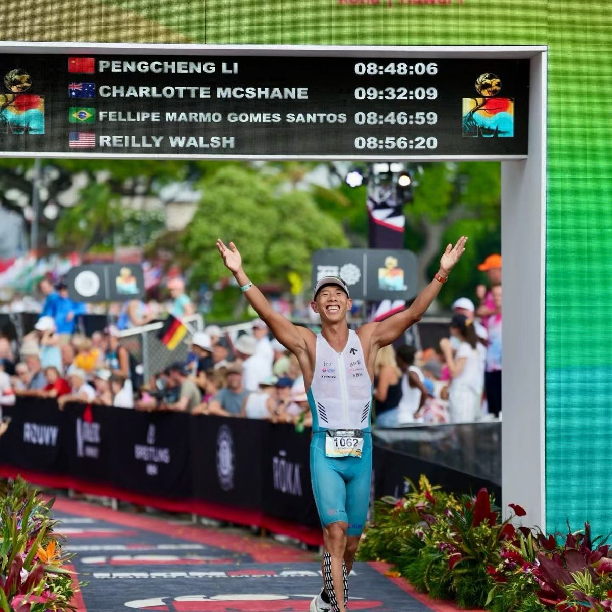 Li Pengcheng finishing at Kona 2026, the scoreboard showing 08:48:06