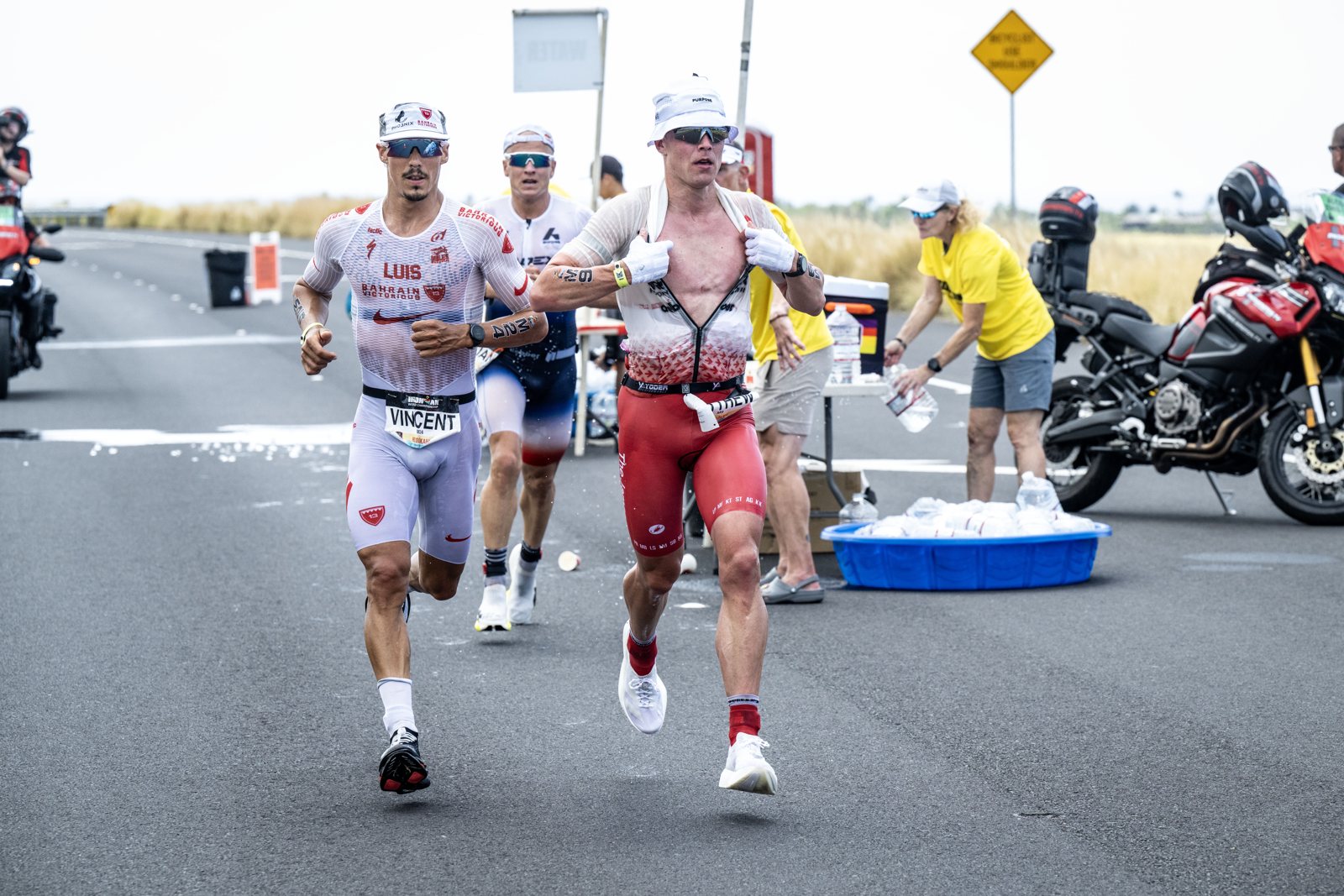 Vincent Luis（左）與其他職業選手在 2026 Kona 馬拉松賽段經過補給站