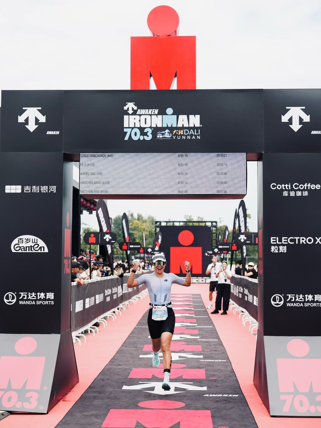 選手高舉雙手通過 IRONMAN 70.3 大理的終點拱門